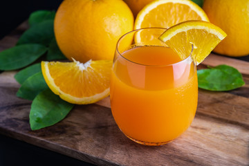Glass of orange juice with fresh fruits on wooden floor