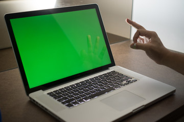 A laptop with green screen and hand gesture