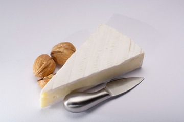 Piece of french soft-ripened white mold cow milk cheese brie produced in Seine-et-Marne region, France, isolated on white