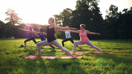 Mixed age group of people practicing yoga outside in the park while sunset - Powered by Adobe