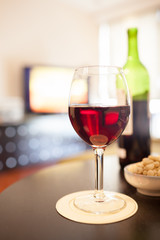 glass of wine and bottle of red wine in home setting