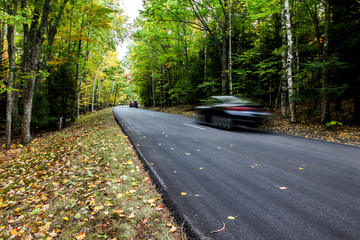 Road in autumn with foliage colors and cars