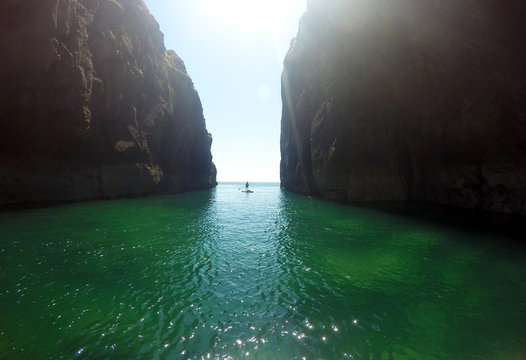 Paddle boarder exploring cliffs and rock architecture on the Pembrokeshire Coast, Wales