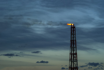 Fototapeta na wymiar industrial flare for the combustion of associated petroleum gas against the background of sky
