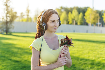 Beautiful modern woman listening to music with her headphones on the background of nature in autumn Sunny Park