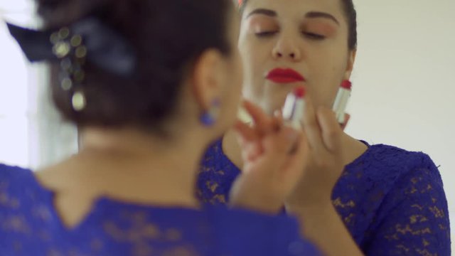 Fat girl paints her lips in front of a mirror