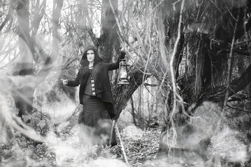 Obraz premium Kobieta w stroju czarownicy w gęstym lesie