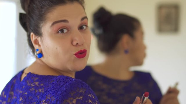 Fat girl paints her lips in front of a mirror