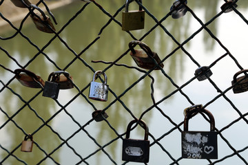 Padlocks as symbol of love on a  wire fence bridge with water background. Locks bridge.