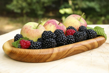 Apples and berries on a wooden plate, close-up