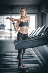 Fit young woman caucasian running on machine treadmill workout in gym. Glad smiling girl is enjoy with her training process. Concept of fitness, healthy life, Sport, Lifestyle.
