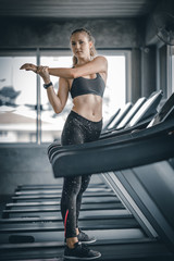 Fit young woman caucasian running on machine treadmill workout in gym. Glad smiling girl is enjoy with her training process. Concept of fitness, healthy life, Sport, Lifestyle.