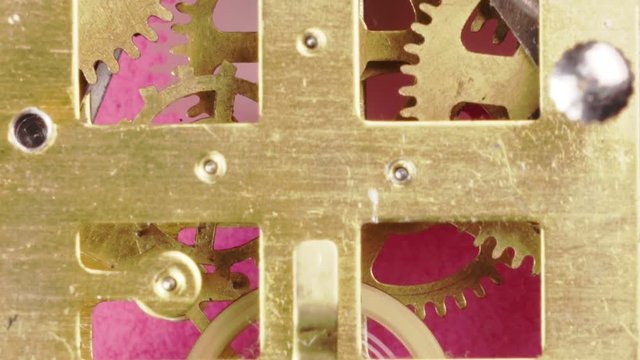 close up and zooming out detail of running clock or watch machinnery on a pink background. Copy space available and suitable for time concepts
