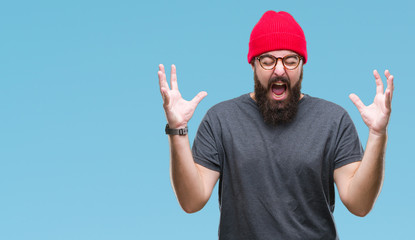 Naklejka premium Young caucasian hipster man wearing glasses over isolated background celebrating mad and crazy for success with arms raised and closed eyes screaming excited. Winner concept