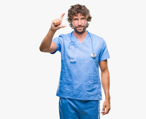 Handsome hispanic surgeon doctor man over isolated background smiling and confident gesturing with hand doing size sign with fingers while looking and the camera. Measure concept.