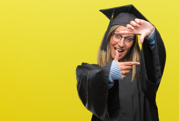 Young beautiful woman wearing graduated uniform over isolated background smiling making frame with hands and fingers with happy face. Creativity and photography concept.