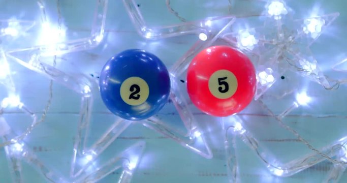 Flat lay two billiard balls with number 25 and glowing Christmas star on wooden background. Shot in 4k resolution