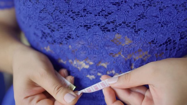 Fat girl in a blue dress measures her volume