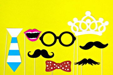 Moustache, tie, glasses, red mouth on wooden sticks against a bright yellow background Month donations concept for the study and control of prostate cancer and other male diseases Mock up Flat lay 