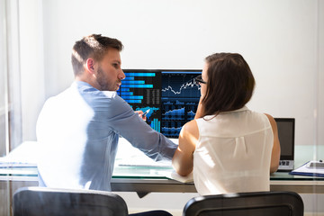 Two Stock Market Brokers Discussing Graphs On Computer