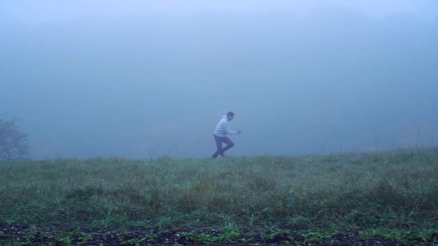 Man running on the grass in the fog
