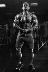Fototapeta na wymiar White Muscular man fitness model is posing in the gym and straining muscles BW