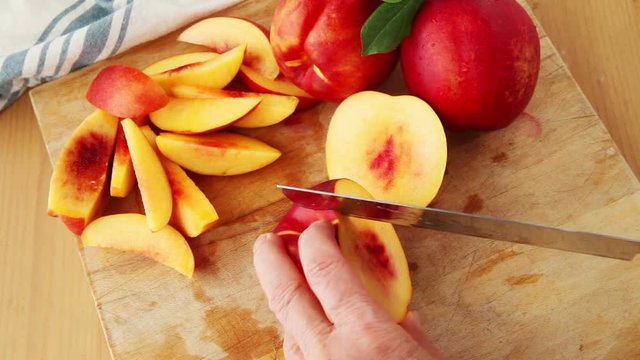 A woman cuts up fresh nectarines on a cutting board