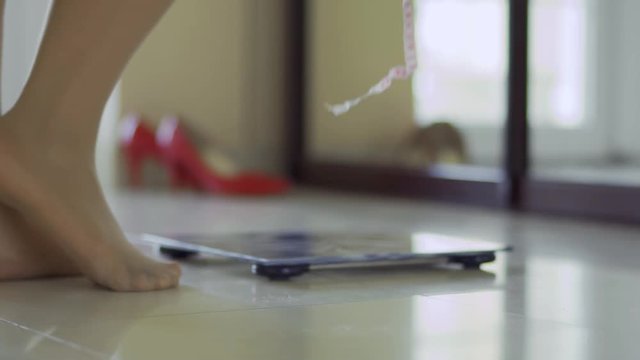Legs of a full girl stand near the scales