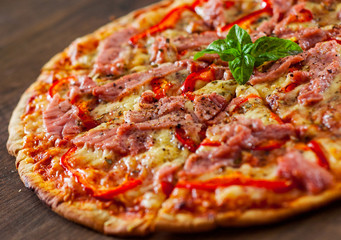 slices of Pizza with Mozzarella cheese, ham, pepper, meat, Tomatoes, Spices and Fresh Basil. Italian pizza on wooden background