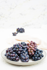 Berries of ripe blue grapes on a plate on a table. Harvesting in autumn