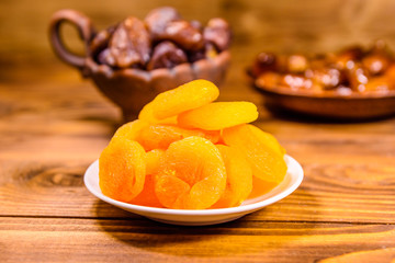 Dried apricots and date fruits on wooden table