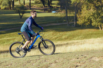 Naklejka premium A cyclist rides the hills, Beautiful portrait of a guy on a blue bicycle 