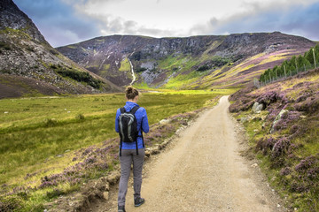 Fototapeta premium Tourist walking in the Cairngorm Mountains, south of the Grampians. Pathway around Loch Lee, Angus, Aberdeenshire, Scotland, UK.