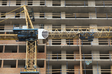 Facade and crane near a modern concrete building under construction.