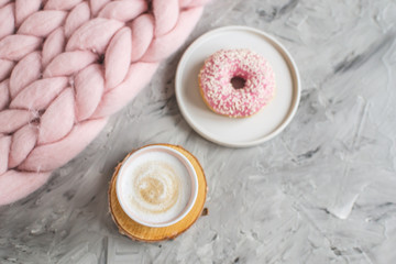 Fototapeta na wymiar Cup with cappuccino, doughnut, pink pastel giant blanket, flowers, bedroom, morning concept