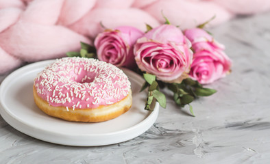 Cup with cappuccino, doughnut, pink pastel giant blanket, flowers, bedroom, morning concept