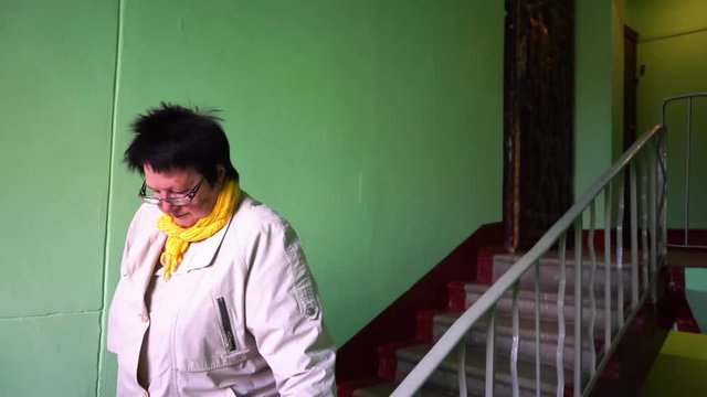 an elderly woman comes down the stairs in the entrance MLS 2