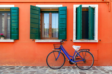 Fototapeta na wymiar Bicycle with a basket by the wall of colorful house in Burano, Venice, Italy.