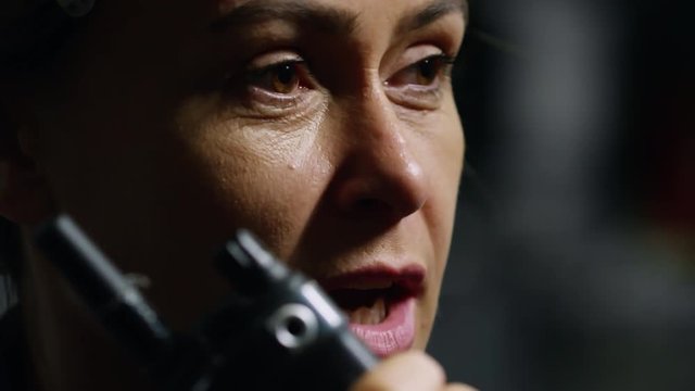 Extreme close up shot of mature female engineer speaking to colleagues using two way hand-held radio
