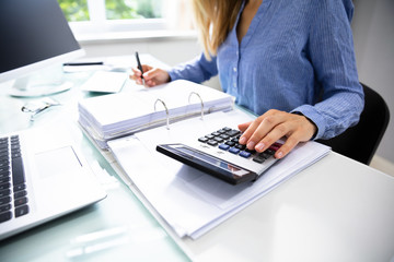 Businesswoman Calculating Invoice In Office