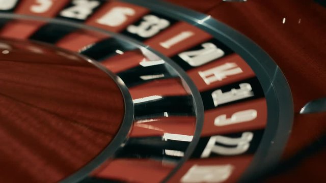 Wooden roulette wheel with black and red sectors. Close up white ball stopped on black sector in casino roulette. Classic roulette table in luxury casino. Rotating gambling machine