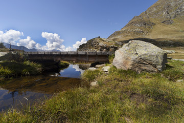 Fototapeta na wymiar riflesso delle nubi in un piccolo fiume di montagna sotto un ponte