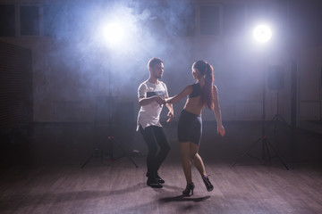 Skillful dancers performing in the dark room under the concert light and smoke. Sensual couple performing an artistic and emotional contemporary dance