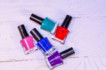 Different nail polishes on a wooden table. Top view