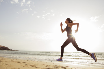 Young sport woman running in the morning on the beach.