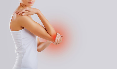 Obraz premium Pain, injury in the elbow joint. A woman holds her hand to her elbow.
