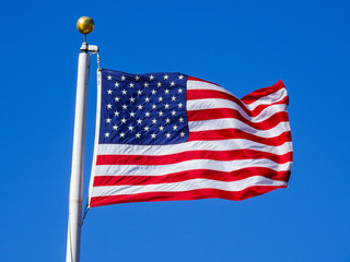 USA flag int he wind with brass pole head