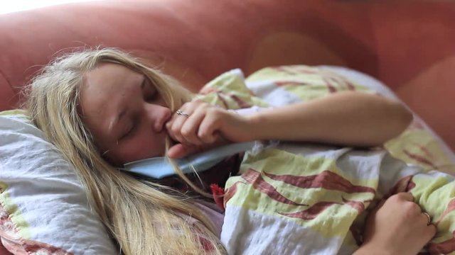 girl is sick with grip and measures the temperature