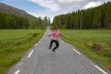 Young woman happy on country road in Northern Norway