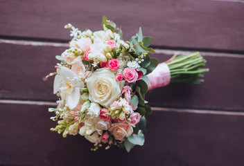 Wedding bouquet on a wooden background. Pink and cream roses. Flowers in pastel colors. White orchid.